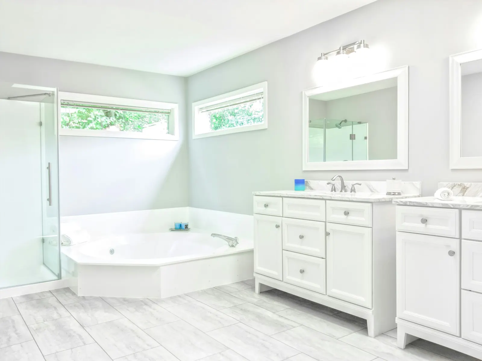 White bathroom with a corner tub, glass shower and double vanity