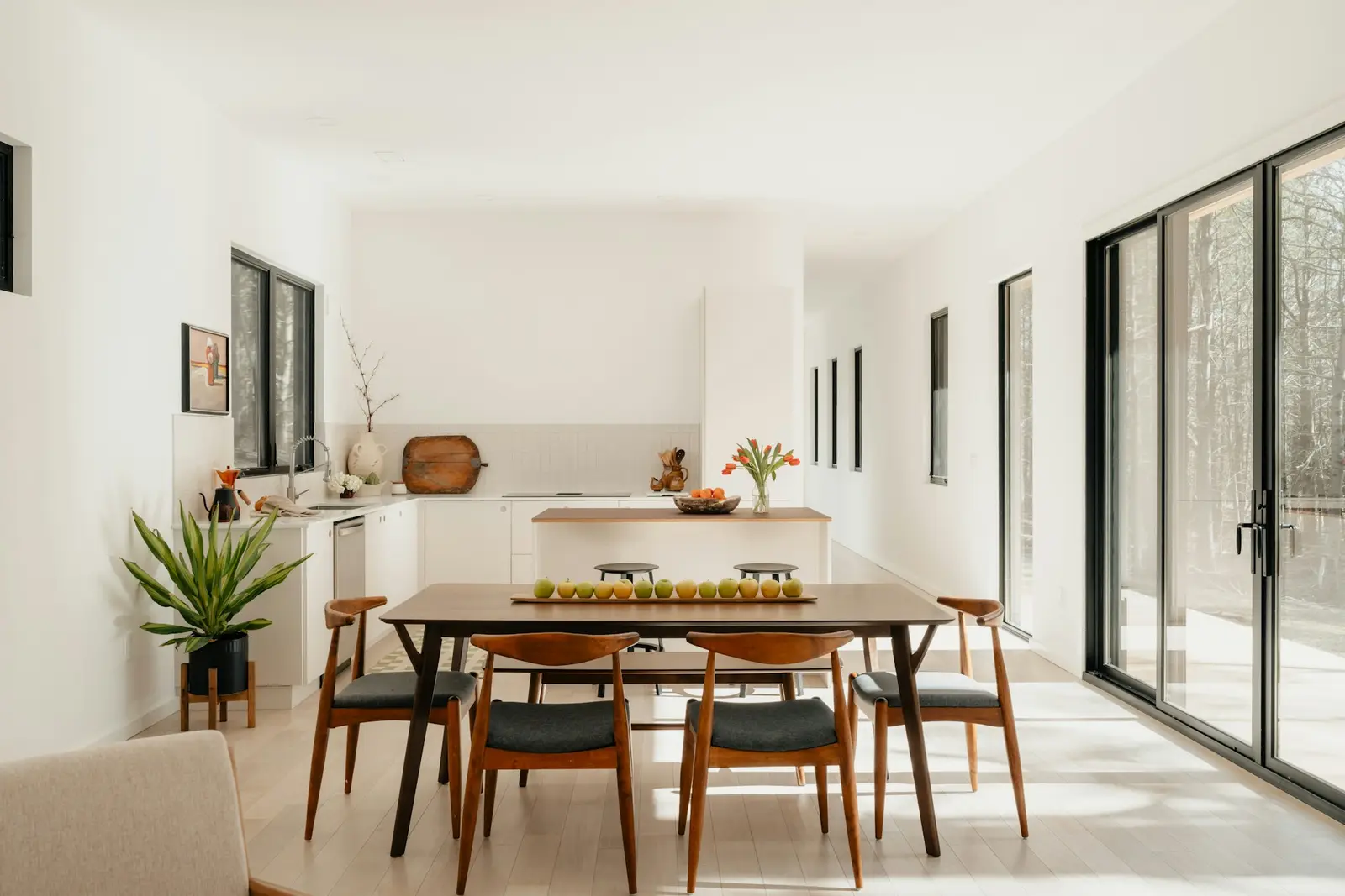 Sunny open dining area with a walnut table, six chairs and the kitchen beyond