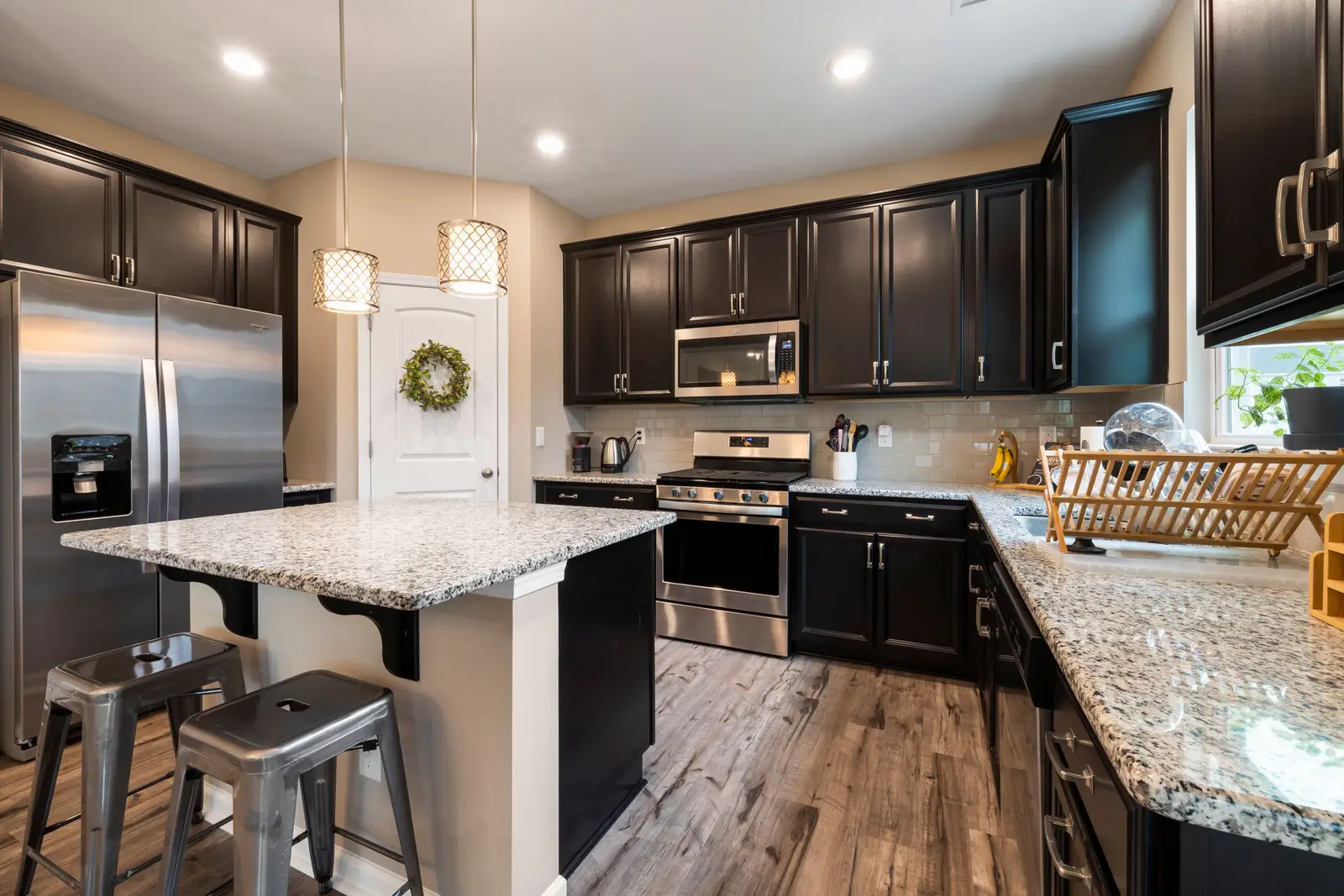 Dark espresso kitchen with a granite island, stainless appliances and metal stools