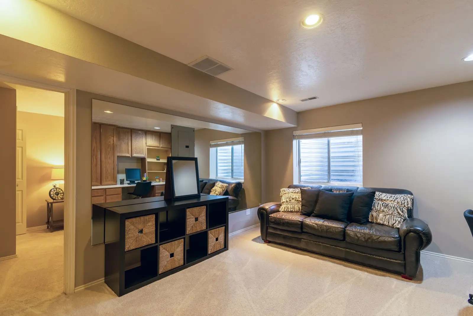 Finished basement family room with a leather sofa, carpet and small windows