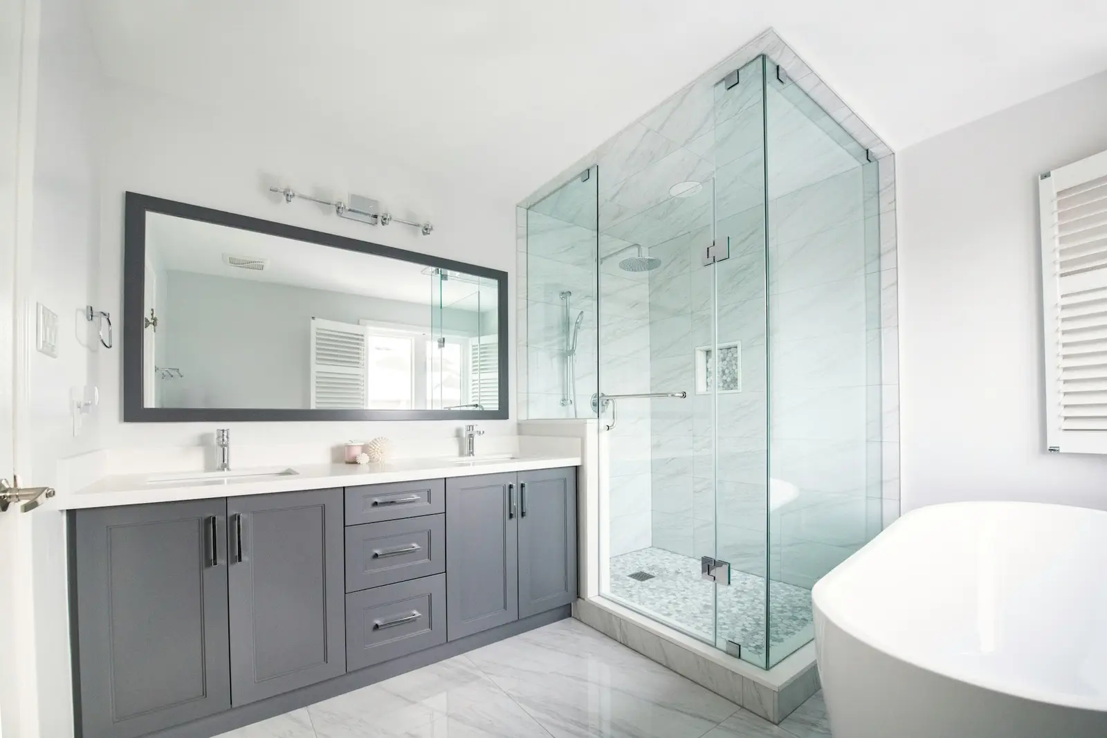 Ensuite bathroom with a grey double vanity, glass shower and freestanding tub