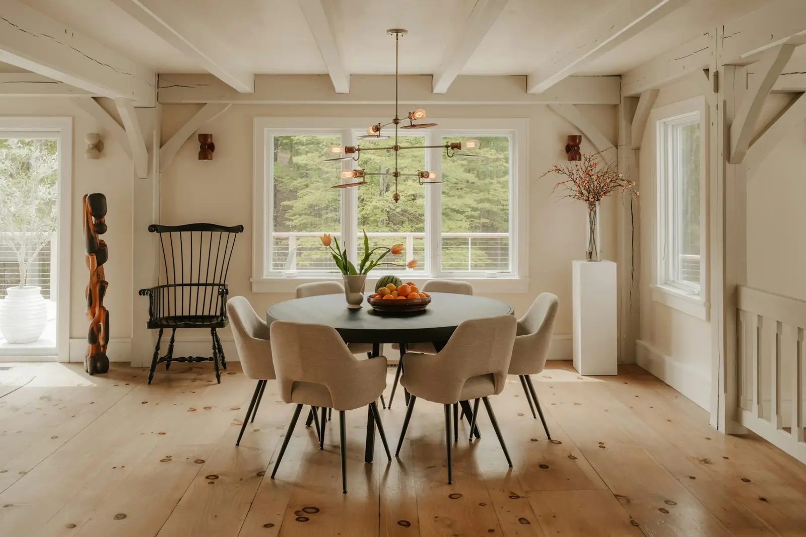 Dining room with exposed wooden beams, wide plank floors and a round table